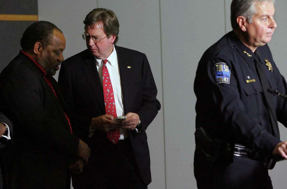 Tulsa Mayor Dewey Bartlett, center, chats with city councilor Jack Henderson as Tulsa Chief of Police Chuck Jordan, right, speaks during a news conference at the Tulsa Police Department, Saturday, April 7, 2012 in downtown Tulsa, Okla. Police believe the same attacker or attackers are behind a series of early-morning shootings in which three people were killed and two others were critically wounded within a three-mile span of north Tulsa. (AP Photo/Tulsa World, James Gibbard) ONLINE OUT; TV OUT; TULSA OUT
