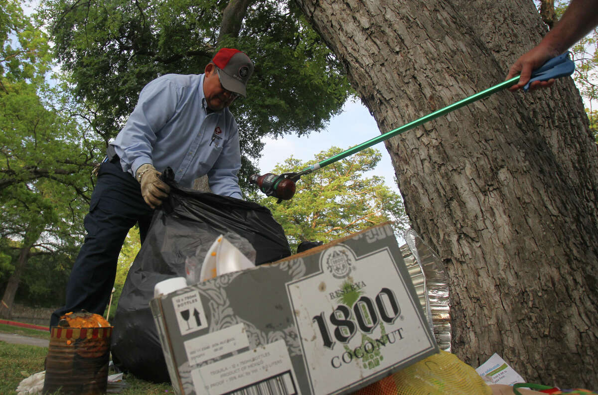 San Antonio Parks and Recreation worker Jim Chavez (left) gathers trash as Parks and Recreation worker Mark Lawson (right) gets ready to drop a spent bottle of barbecue sauce into a bag at Brackenridge Park Monday April 9, 2012 the day after Easter celebrations. "We try to get it all cleaned up before noon," Lawson said. John Davenport/San Antonio Express-News