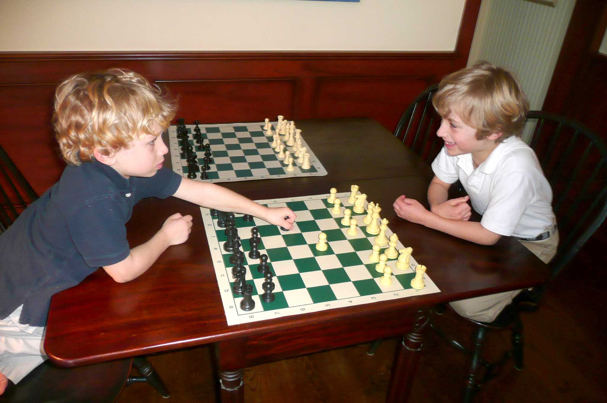 Kids playing chess. Two boys, aged six and eight years, think
