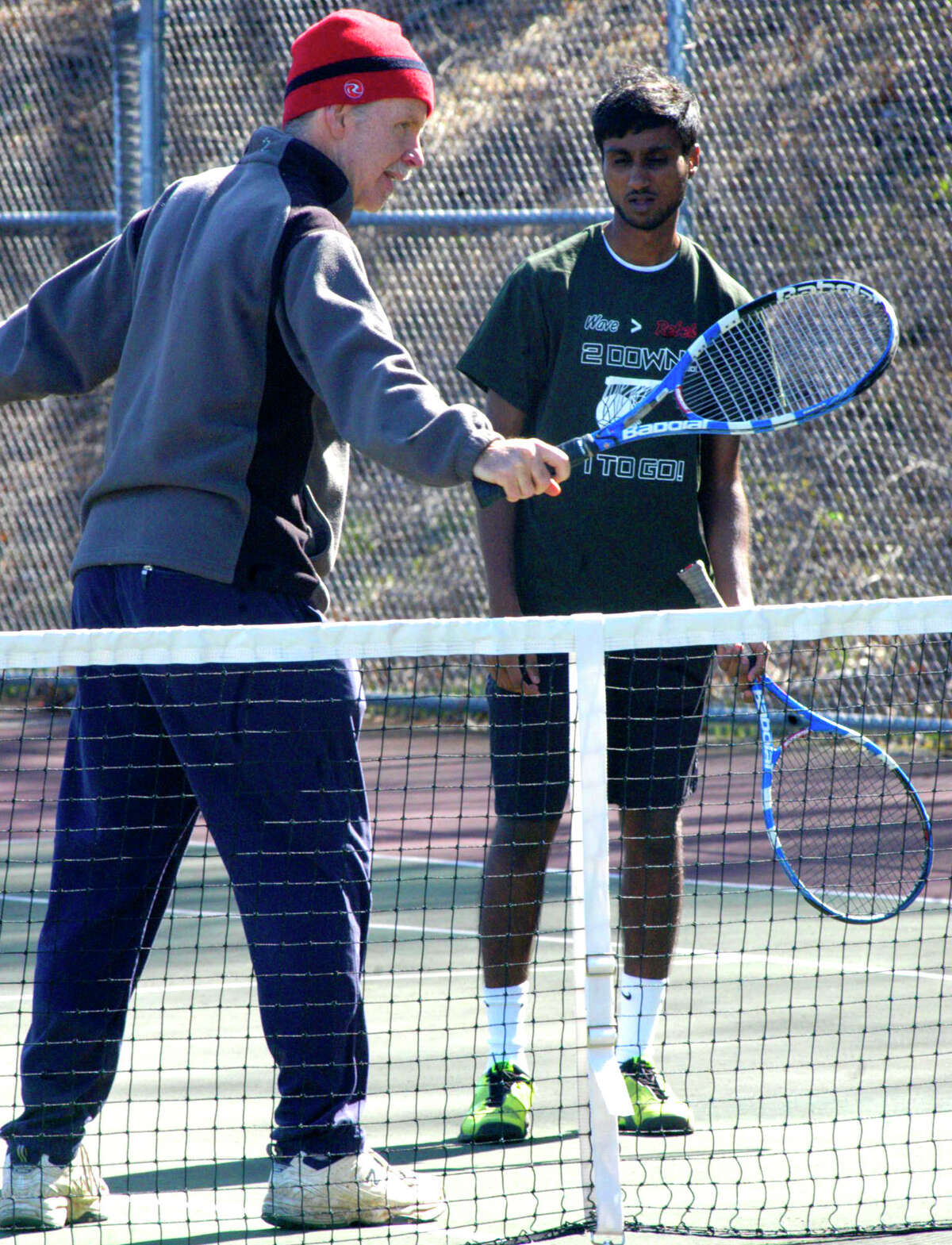 SPECTRUM/Green Wave senior Amar Kandhari studies the backhand technique of coach Joe Marshall during pre-season practice for New Milford High School boys' tennis. April 2012