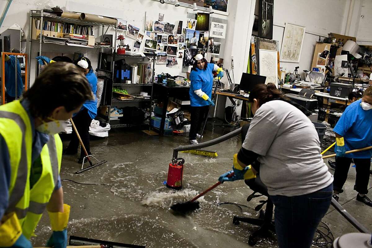 Employees with ServiceMaster Clean work to remove water from a shared studio at Workspace Limited Studios after early Thursday morning rain flooded many businesses and homes on Folsom Street in between 17th and 18th streets in San Francisco, Calif., April 12, 2012.