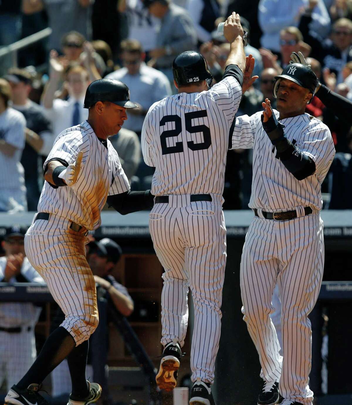 New York Yankees Alex Rodriguez, left, and Robisnon Cano, right greet Mark Teixeira (25) after the three of them scored on Nick Swisher's, first-inning three-run double off Los Angeles Angels starting pitcher Ervin Santana during the Yankees home opener baseball game against the Angels at Yankee Stadium in New York, Friday, April 13, 2012.