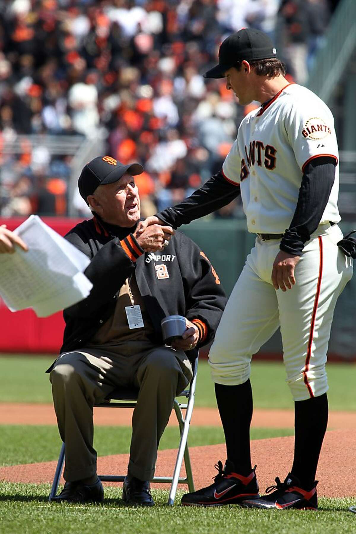 San Francisco Giants great Jim Davenport, seated, former third baseman and baseball manager, shakes hands with Ryan Theriot during a ceremony that honored the New York Giants of old, which won the pennant in 1961-63. The ceremony took place prior to the opening Day baseball game between the Giants and the Pittsburgh Pirates in San Francisco, Friday, April 13, 2012.
