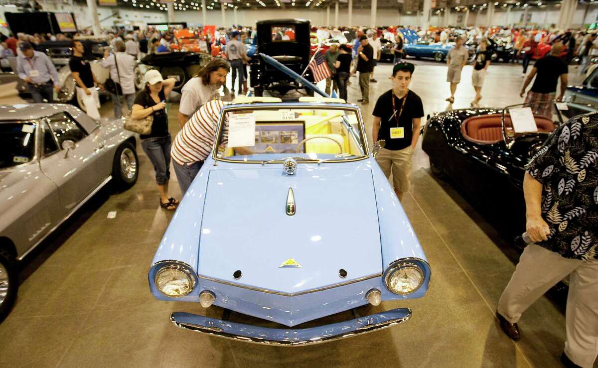 Car enthusiests get a close look at a 1964 Amphicar convertible vehicle as they visit Mecum Auctions Muscle Cars & More event.