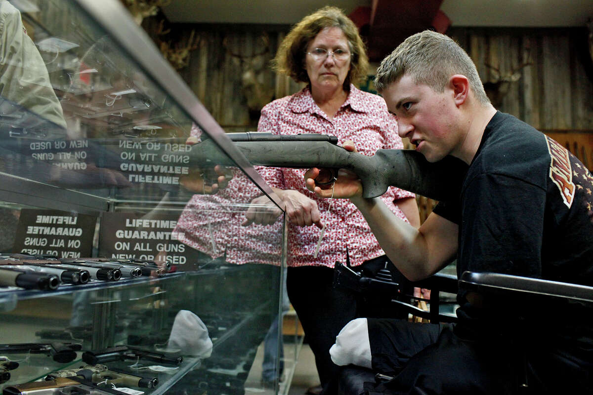 Saralee Trimble watches as her son, Army Pfc. Kevin Trimble, 19, shops for a hunting rifle at Dury's Gun Shop in San Antonio on Wednesday, March 7, 2012. Trimble was looking to buy his own rifle, since he's been borrowing one, for hunting trips with wounded warriors.