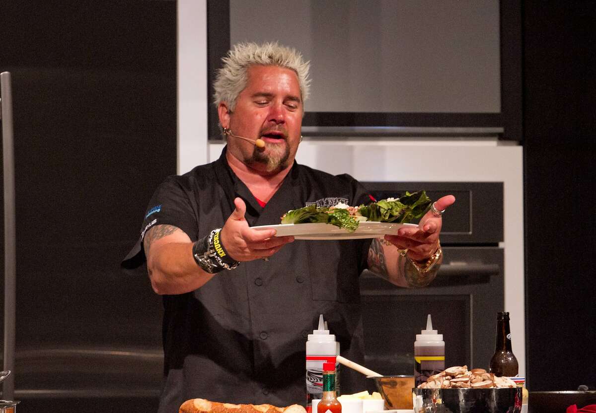 Chef Guy Fieri presents a dish to the crowd at his interactive dinner during the Pebble Beach Food and Wine event in Pebble Beach, Calif. on Saturday, April 14th, 2012.