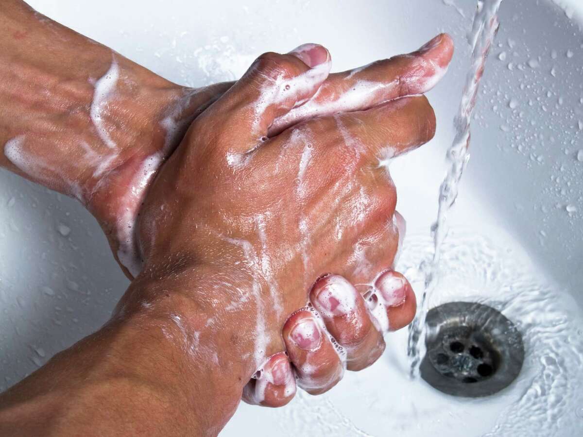 Man washing hands with soap at sink.