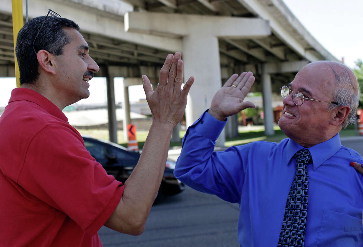 Richard Salas (right) high fives Fernando Villarreal, operations officer of the Fiesta San Antonio Commission, after Villarreal confirmed that new bleachers will not block the view from the spot Salas saves every year.