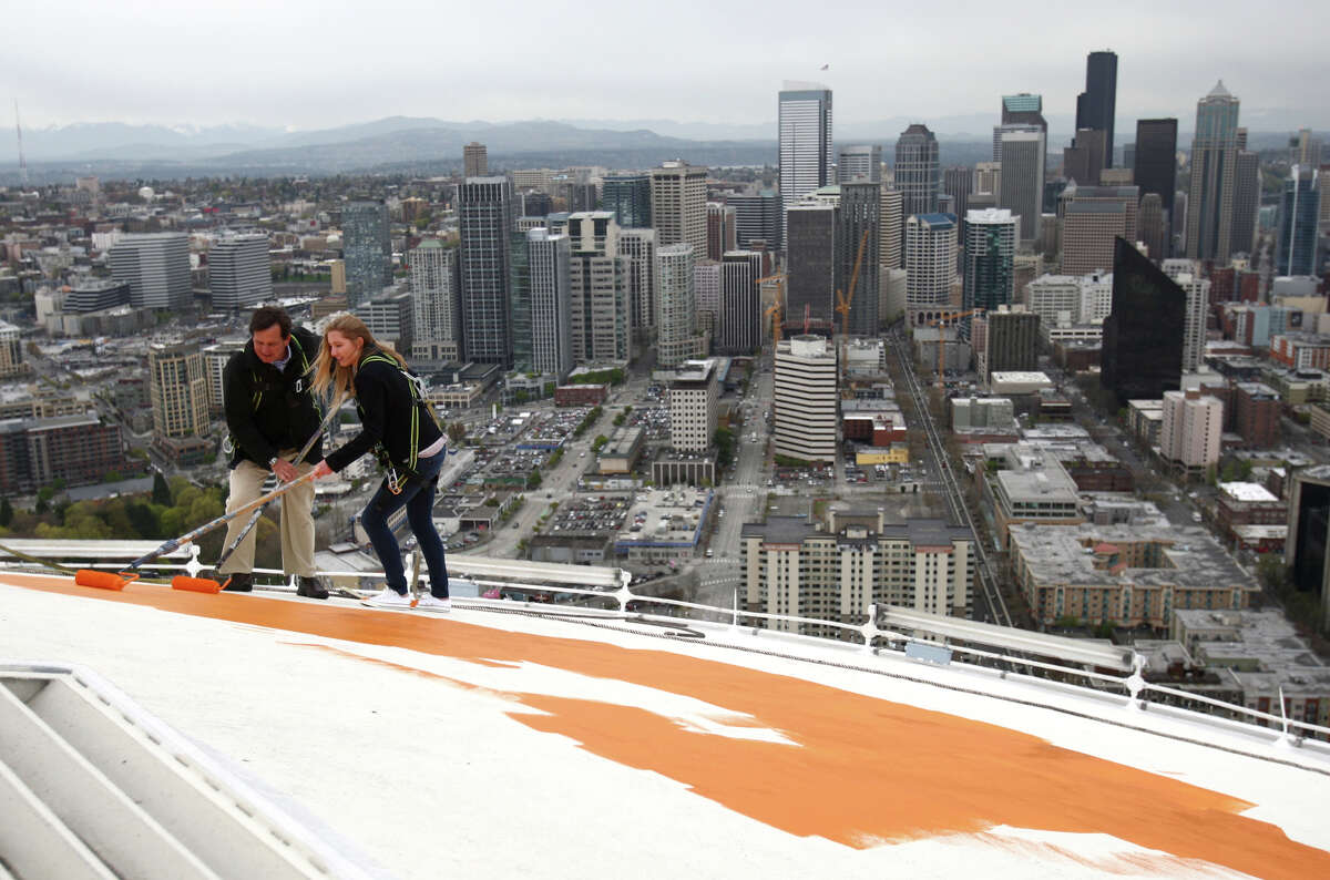 Jeff Wright and Mauren Wright, 15, Jeff's daughter, begin painting the roof of the Space Needle its original 'Galaxy Gold' on Tuesday, April 17, 2012. Jeff Wright's father Howard S. Wright built the Space Needle.