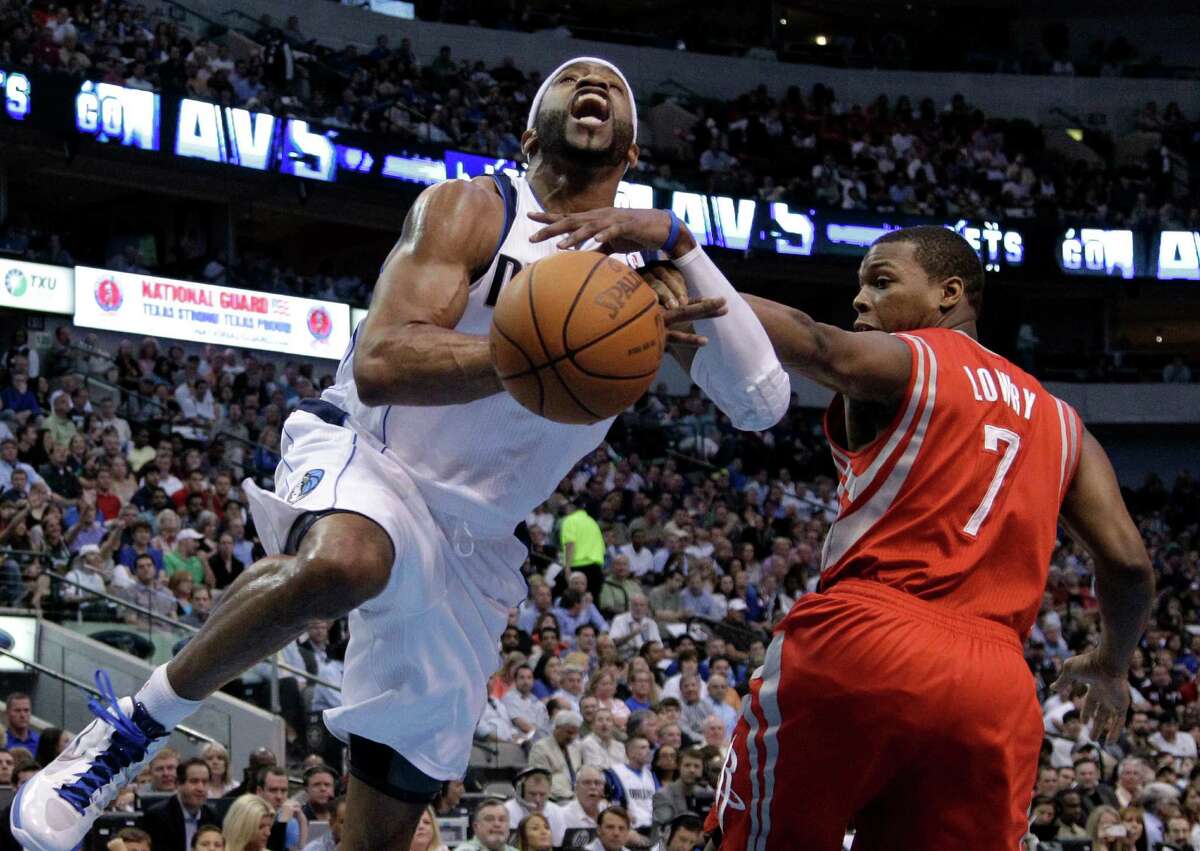 Dallas Mavericks' Vince Carter, left, if fouled by Houston Rockets' Kyle Lowry (7) while going to the basket in the first half of an NBA basketball game on Wednesday, April 18, 2012, in Dallas. (AP Photo/Tony Gutierrez)