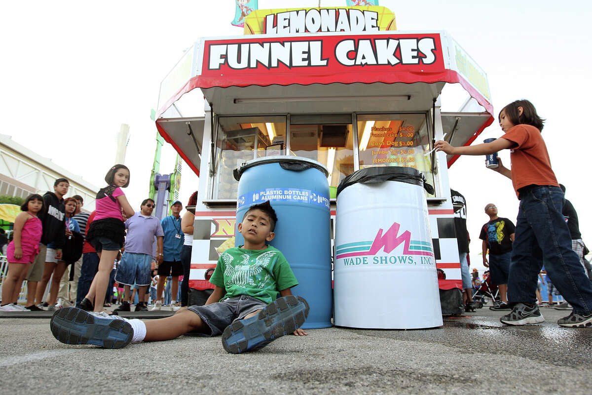 Elijah Jasso, 9, feels the effects of the Gravitron on the first day of the Fiesta Carnival at Lot C of the Alamodome. Recycling trash cans have been placed alongside regular trash cans at the carnival.