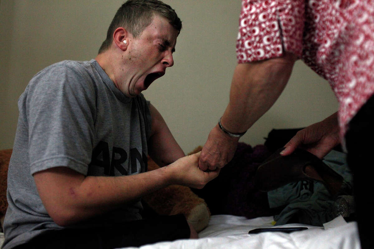 Army Pfc. Kevin Trimble, 19, yawns moments after waking up as his mother, Saralee Trimble, helps him start his day at dawn at Powless Guest House at Fort Sam Houston in San Antonio on Wednesday, March 7, 2012.