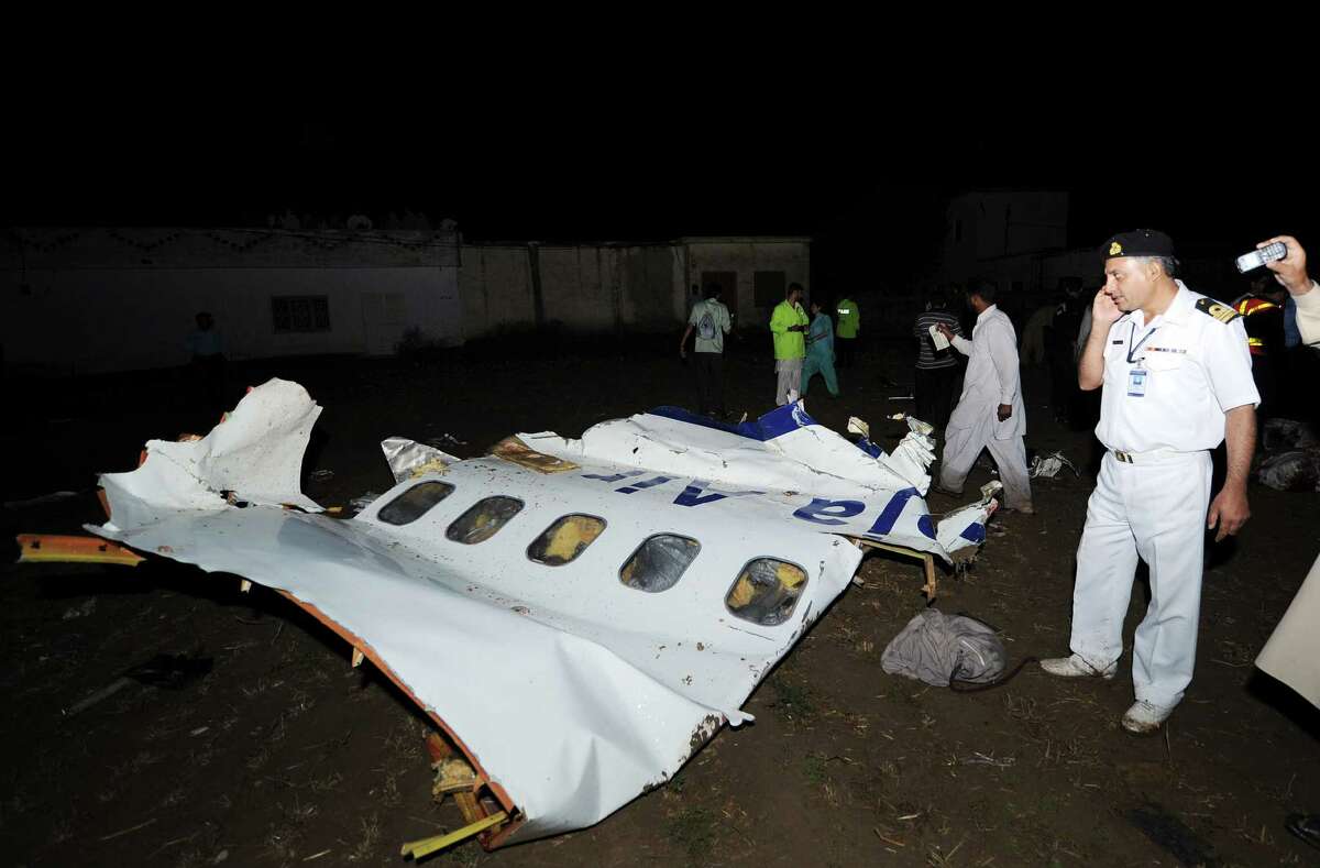 A Pakistani airline official (R) stands next to the wreckage of a Bhoja Air Boeing 737 plane following a crash in the outskirts of Islamabad on April 20, 2012. Up to 130 people are feared dead after a Boeing 737 crashed while trying to land in bad weather near the Pakistani capital Islamabad on April 20, officials said. The Bhoja Air flight from Karachi came down outside Islamabad's international airport, police official Fazle Akbar said, adding that emergency teams have been sent to the site. AFP PHOTO / AAMIR QURESHI