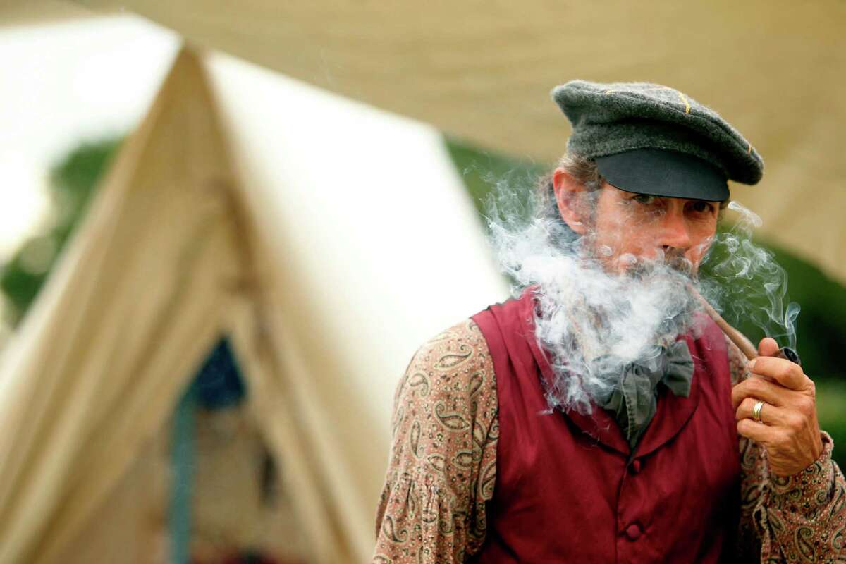 Jim Glover, dressed in period clothing, smokes a pipe at the Texas Army civilian camp and prepares for the re-enactment of the Battle of San Jacinto on Friday.