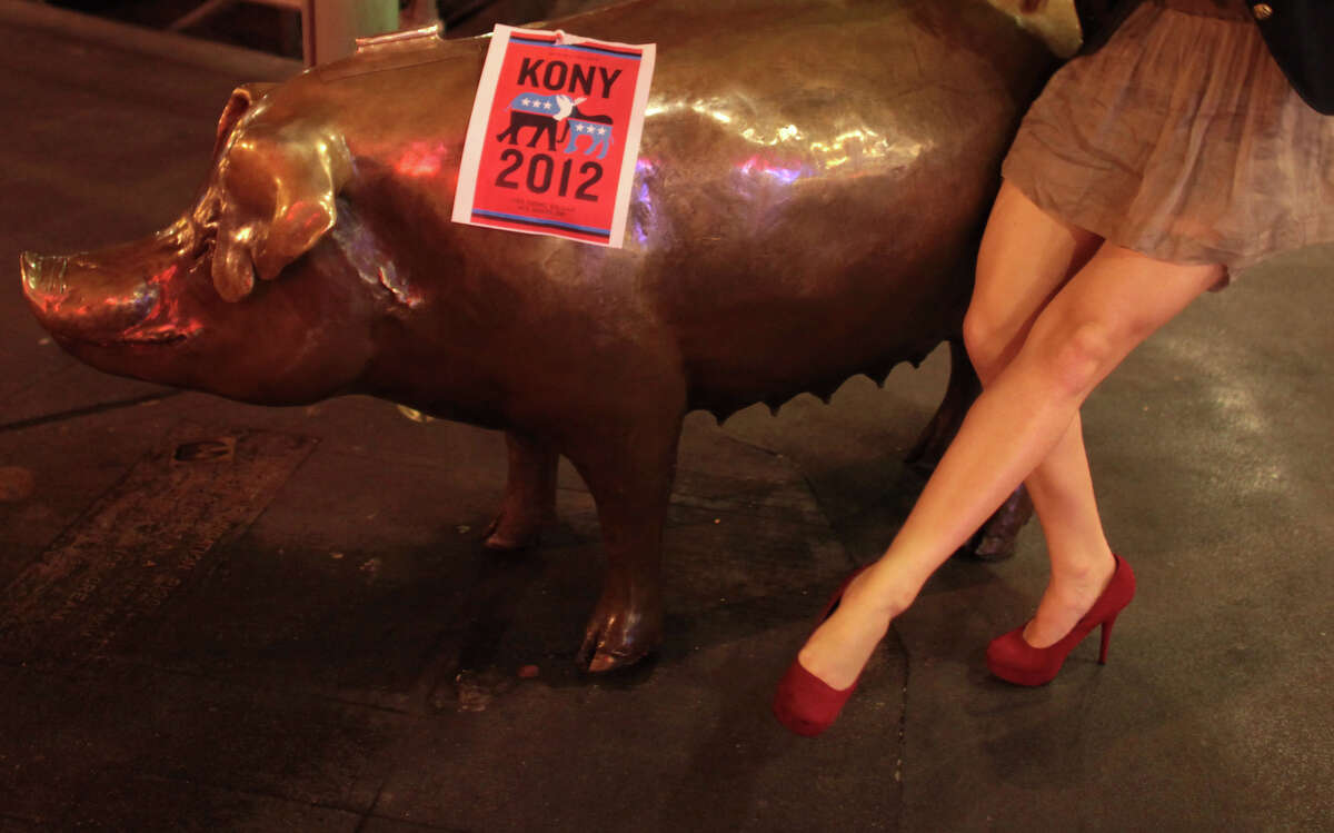 A passerby shows that her shoes match a Kony 2012 poster on Rachel the pig at Pike Place Market during "Cover the Night," part of the Kony 2012 campaign. The controversial campaign by the group Invisible Children is working to bring attention to Joseph Kony, leader of the Lord's Resistance Army in Africa. Photographed on Friday, April 20, 2012.