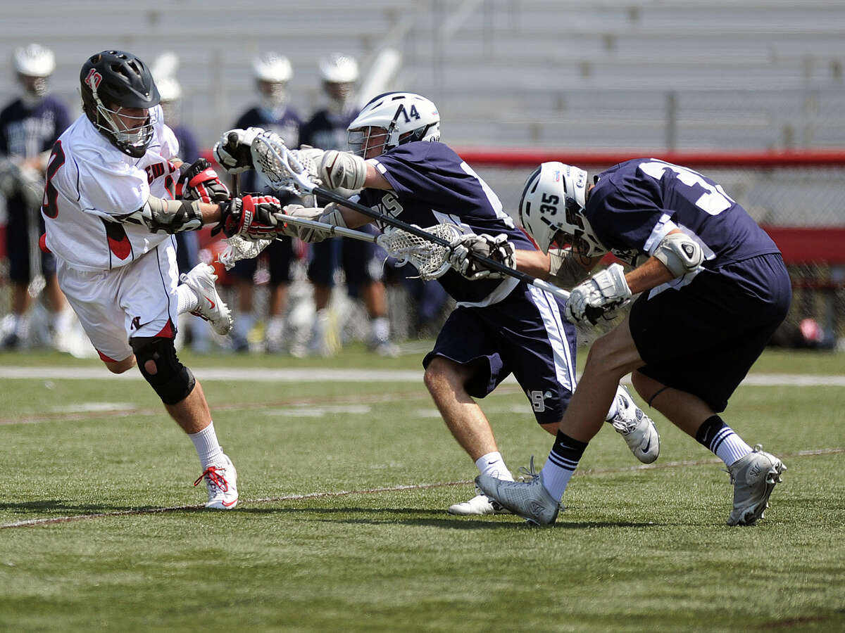 New Canaan's Puck Richardson takes a shot as Staples' Patrick Lesch, center, and Adam Levinson, right, reach to block his shot during Saturday's lacrosse game at New Canaan High School on April 21, 2012.