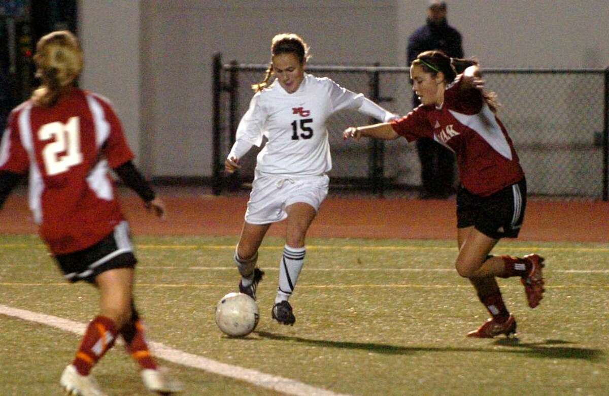 New Canaan's #15 Jana Persky, center, prepares to kick a goal, as Masuk's #22 Jillian Scholler, right, tries to block the shot, during Class L Semifinals, in Fairfield, Conn. on Wednesday Nov. 18, 2009. Masuk was defeated by New Canaan 3-0.