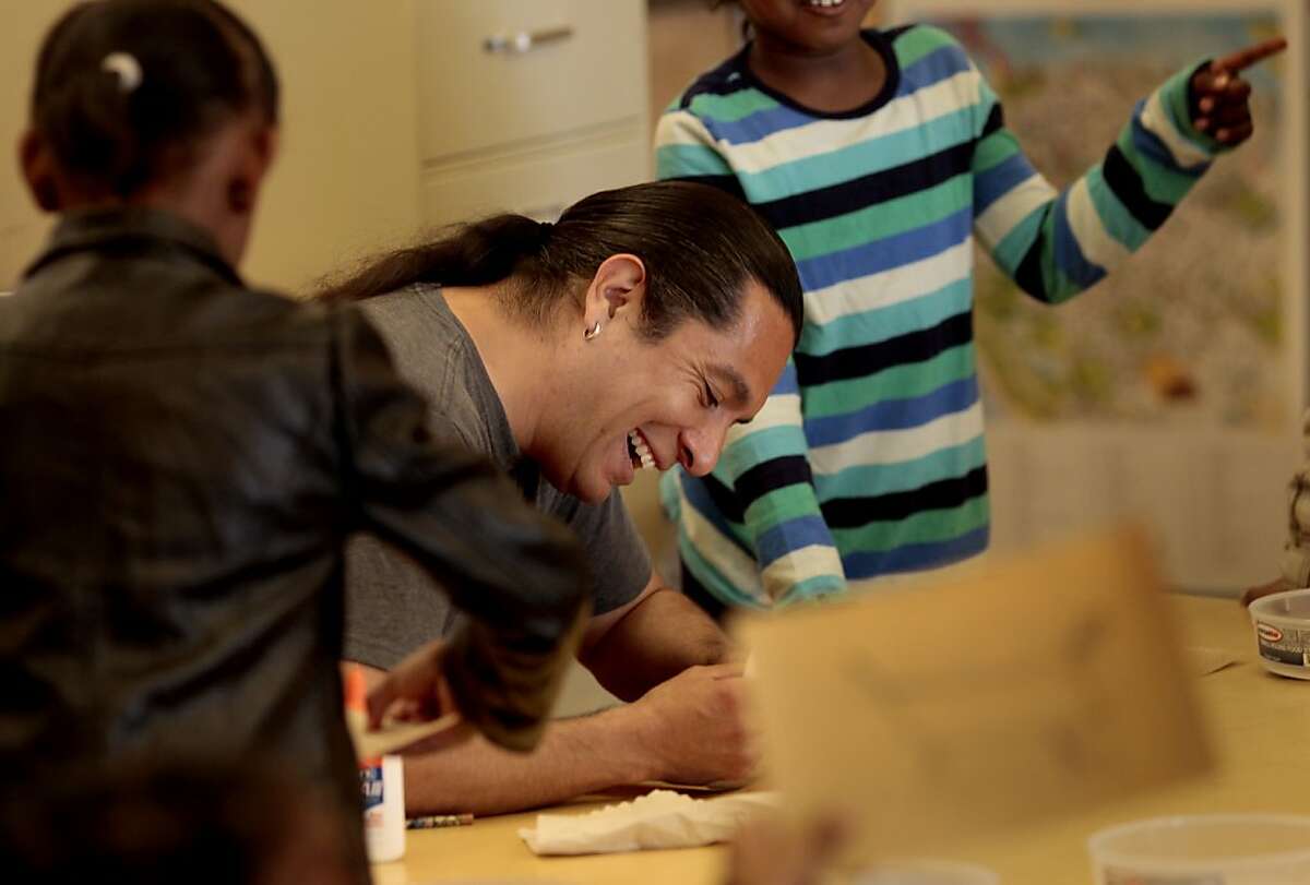 Eddie Madril laughs as he applies glue to the students Native American sand paintings. Eddie Madril is an artist in residence that teaches Native American culture and dance at Tenderloin Community School.