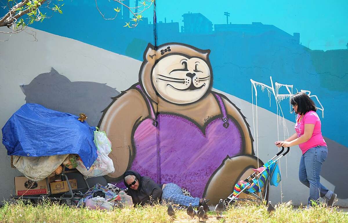 A homeless woman lays down beside her belongings in front of a wall of graffiti as a woman pushes a child in a stroller by on April 19, 2012 in Los Angeles, California. New claims for US unemployment benefits inched lower last week, government data showed, in a report casting a cloud on the recovery in the labor market. The new claims numbers, indicating the pace of layoffs, came amid signs of a sputtering recovery in the job market, where the unemployment rate fell to 8.2 percent in March from 8.3 percent in February but businesses put the brakes on hiring. AFP PHOTO / Frederic J. BROWN (Photo credit should read FREDERIC J. BROWN/AFP/Getty Images)