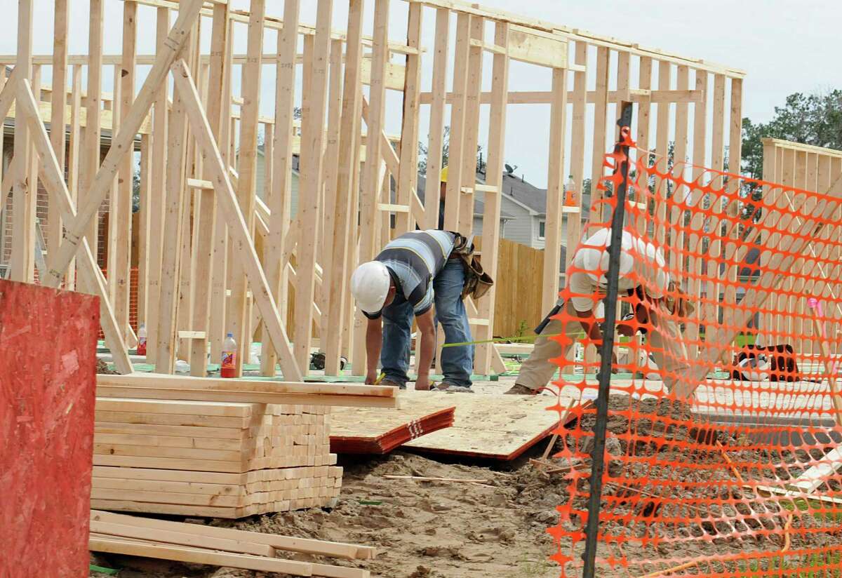 Construction workers gather lumber for framing the first floor of a new home in the King's Mill subdivision in Kingwood.
