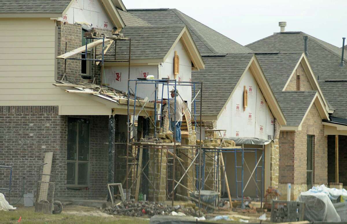 Workers add brick and rock to the front of a new home in the King's Mill subdivision in Kingwood. King's Mill is located one mile east of U.S. 59 on Northpark Drive. The 213-acre development is slated to have 911 homes.