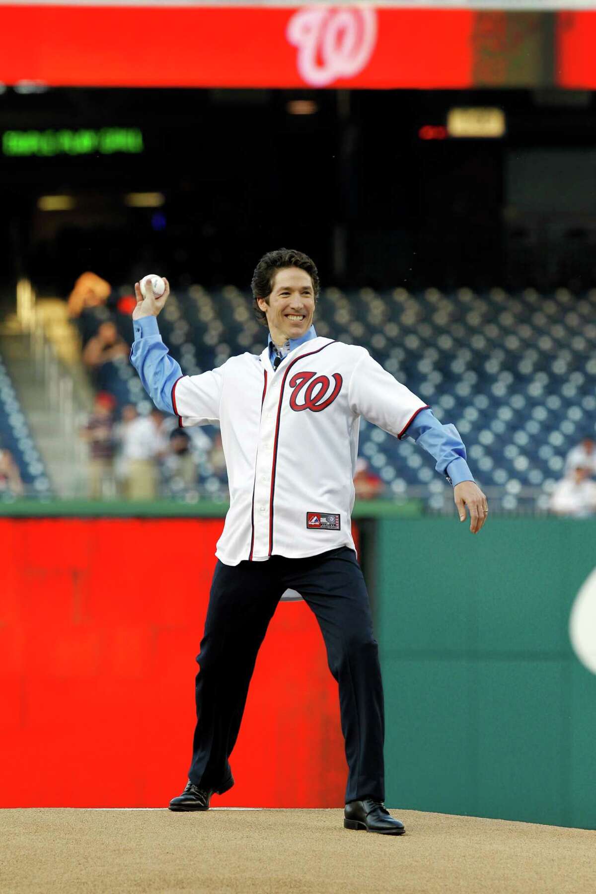 Joel Osteen throws out the ceremonial first pitch prior to a Washington Nationals baseball game against the Houston Astros in Washington, April 16, 2012. (AP Photo/Ann Heisenfelt)
