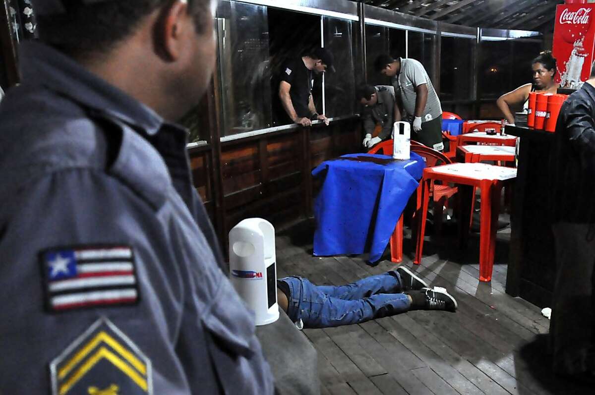 The body of Brazilian journalist Decio Sa, center, lies on the ground after being shot at a restaurant and bar in Sao Luis, Maranhao state, Brazil, Monday, April 23, 2012. Sa, a political reporter for the O Estado do Maranhao newspaper in northeastern Brazil, is at least the fourth journalist slain this year in the South American nation, one of the deadliest for reporters to work in, according to watchdog groups.