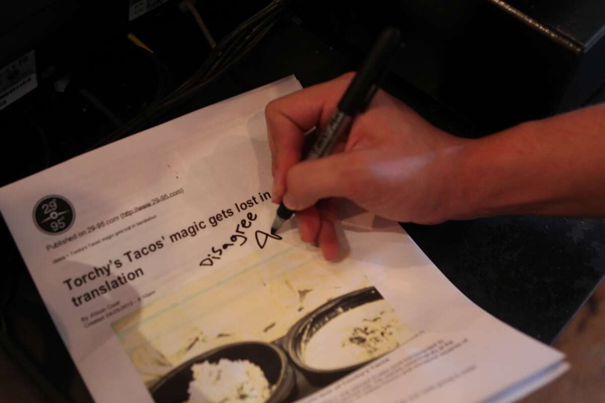Jason Madrid signs a printout of a recent Torchy's review saying he disagrees with it.