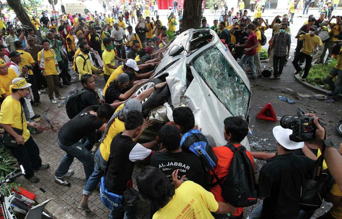 Protesters overturn a police car during a rally to demand for electoral reforms in Kuala Lumpur, Malaysia, Saturday, April 28, 2012. Police unleashed tear gas and chemical-laced water at thousands of demonstrators who staged one of Malaysia's largest street rallies in years, demanding fair rules for national elections expected soon. (AP Photo) MALAYSIA OUT