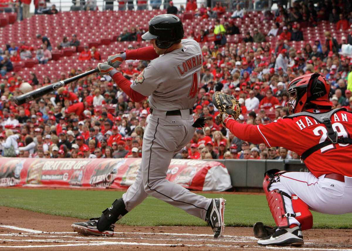 Houston Astros' Jed Lowrie (4) hits an RBI-single off Cincinnati Reds starting pitcher Mat Latos during the first inning of a baseball game on Sunday, April 29, 2012, in Cincinnati. Reds catcher Ryan Hanigan (29)looks on. (AP Photo/David Kohl)