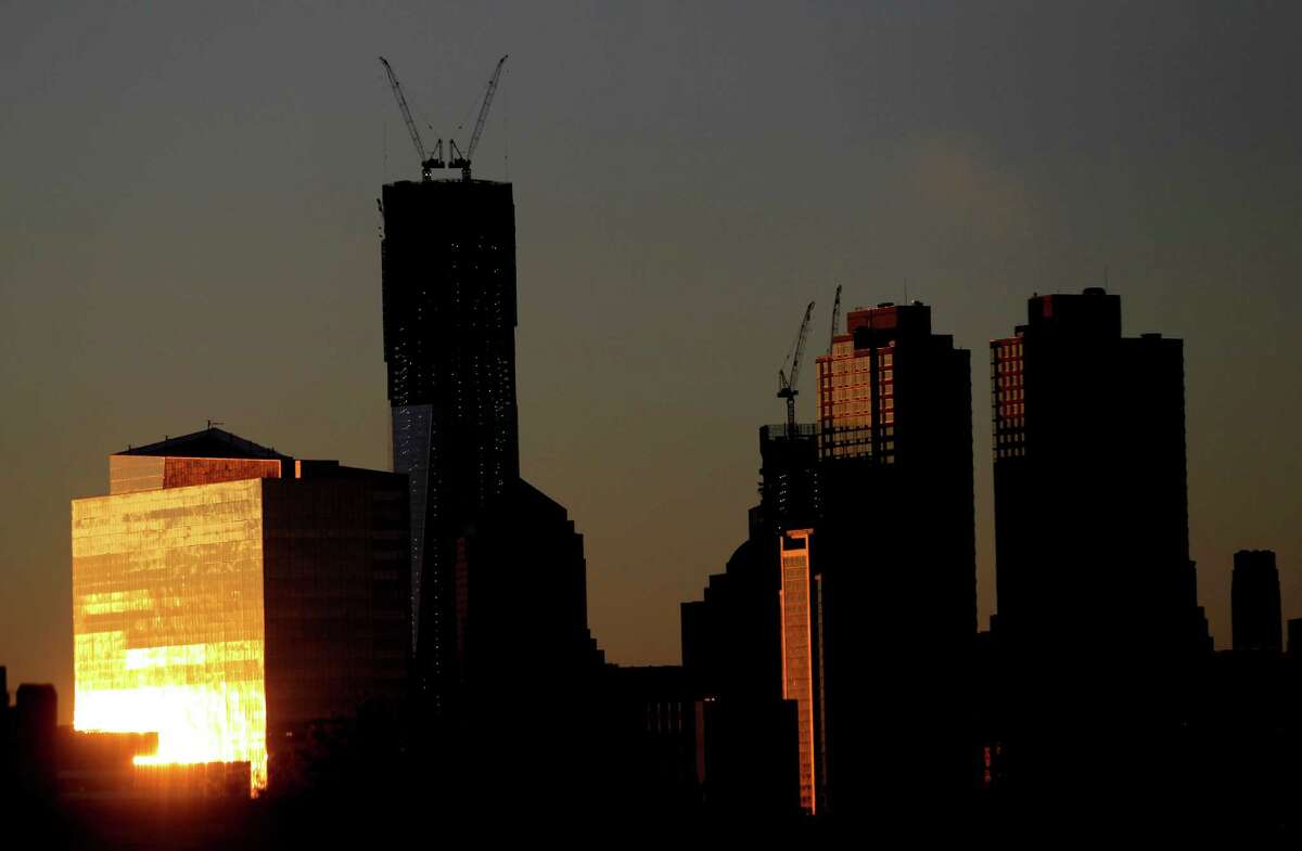 The sun reflects on a building as it rises Monday, including One World Trade Center, center left, in New York as seen from Jersey City, N.J. One World Trade Center, the giant monolith being built to replace the twin towers destroyed in the Sept. 11 attacks, became New York City's tallest skyscraper on Monday.