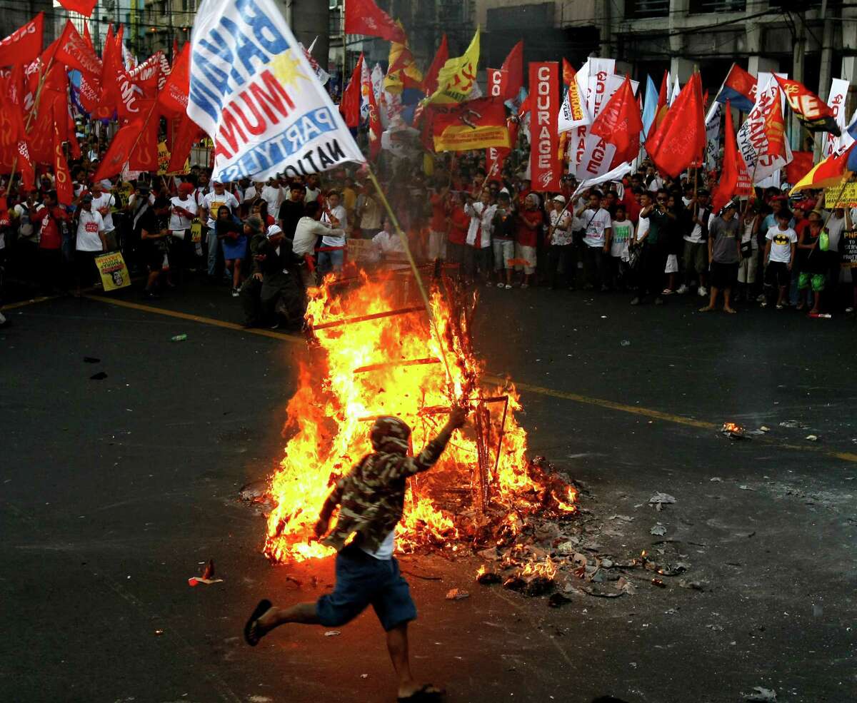 Protesters dance around the burning effigy of Philippine President Benigno Aquino III during a rally near the Presidential Palace in Manila to celebrate international Labor Day known as May Day Tuesday May 1, 2012 in the Philippines. Thousands of workers marched under a brutal sun in Manila to demand a wage increase amid an onslaught of oil price increases, but the Philippine President rejected a $3 daily pay hike which the workers have been demanding since 1999 and warned may worsen inflation, spark layoffs and turn away foreign investors. (AP Photo/Bullit Marquez)