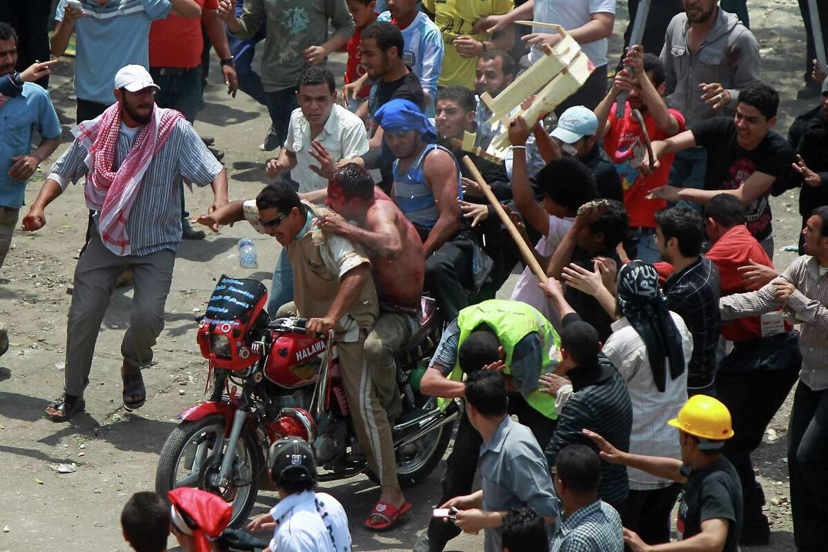 Egyptian protesters beat a man as he tries to escape on the back of a motorcycle after he was accused of attacking demonstrators in the Abbassiya district in Cairo on Wednesday. At least 11 people were killed when attackers stormed an anti-military protest near the defence ministry in Cairo, medics and a security official said. The fate of the man is unknown. (STR/AFP/GettyImages)