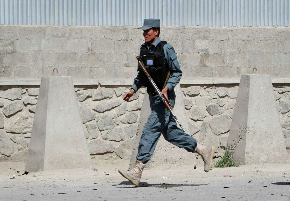 An armed Afghan policeman runs at the of the scene of militants' attack in Kabul, Afghanistan, Wednesday, May 2, 2012. A suicide car bomber and Taliban militants disguised in burqas attacked a compound housing hundreds of foreigners in the Afghan capital on Wednesday, officials and witnesses said. The Taliban said the attack was a response to U.S. President Barack Obama's surprise visit just hours earlier. (AP Photo/Musadeq Sadeq)