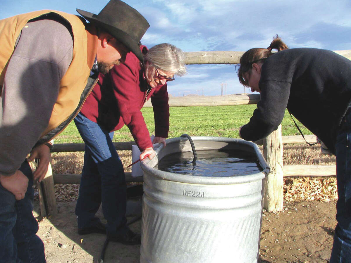 ADVANCE FOR FRIDAY AMS MAY 4 - FILE - In a Nov. 8, 2007 file photo, John Fenton and others examine neighbor Louis Meeks' water in Pavillion, Wyo., where federal officials indicated people shouldn't drink water from 40 wells in and around this central Wyoming farming and ranching community. The U.S. Environmental Protection Agency drew skepticism and mistrust from Wyoming regulators after it privately briefed them more than a month in advance about its first-ever public announcement that hydraulic fracturing, a controversial but favored method for releasing difficult pockets of oil and gas, might have caused groundwater pollution. (AP Photo/Casper Star-Tribune, Dustin Bleizeffer, File)