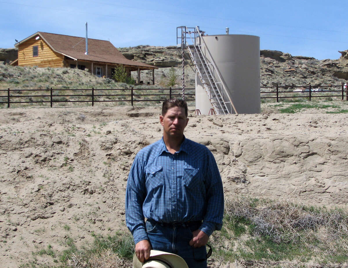 ADVANCE FOR FRIDAY AMS MAY 4 - FILE - A May 22, 2009 picture shows John Fenton, a farmer who lives near Pavillion in central Wyoming, near a tank used in natural gas extraction, in background. Fenton and some of his neighbors blame hydraulic fracturing, or "fracking," for fouling their well water. The U.S. Environmental Protection Agency drew skepticism and mistrust from Wyoming regulators after it privately briefed them more than a month in advance about its first-ever public announcement that hydraulic fracturing, a controversial but favored method for releasing difficult pockets of oil and gas, might have caused groundwater pollution. (AP Photo/Bob Moen, File)