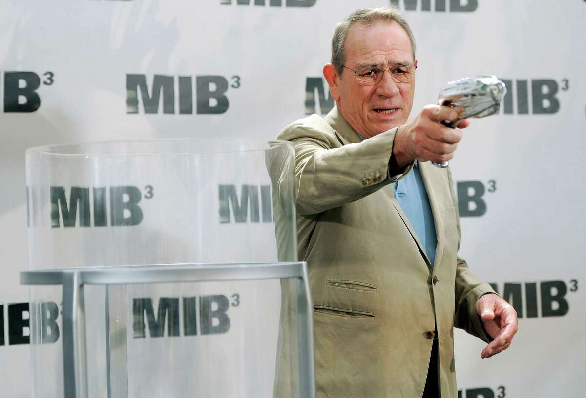 Tommy Lee Jones, a cast member in the upcoming film "Men in Black 3," points a prop gun at photographers before dropping it into a time capsule from the film, during a photo call in Beverly Hills, Calif., Thursday, May 3, 2012. Cast members and the film's director Barry Sonnenfeld dropped props, costume pieces and memorabilia from the film franchise into the time capsule, which will travel across the country before being locked away in a NASA storage facility for 43 years. (AP Photo/Chris Pizzello)