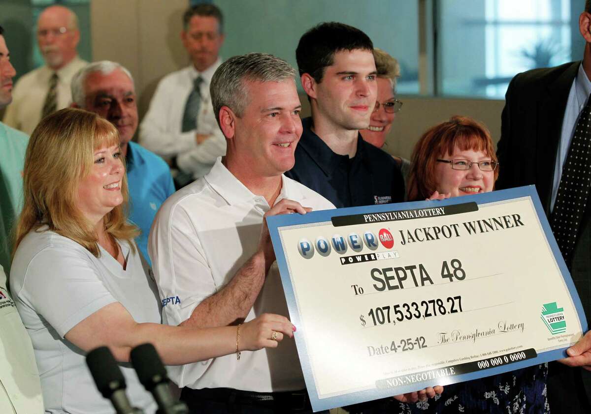 From left, Pamela Schurgot, Robert Landgraf, Matthew Sheridan, Marylouise Wagner, and others of the forty plus Southeastern Pennsylvania Transportation Authority employees who won the Powerball lottery pose for photographs with a ceremonial check during a news conference, Friday, May 4, 2012, in Philadelphia. According to Pennsylvania Lottery officials the prize has a cash value of $107.5 million. (AP Photo/Matt Rourke)