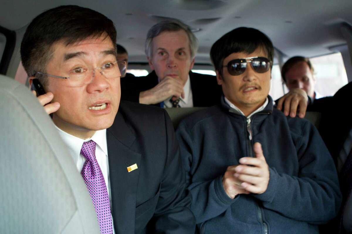 In this photo released by the US Embassy Beijing Press Office, U.S. ambassador to China, Gary Locke, left, makes a phone call as he accompanies blind lawyer Chen Guangcheng, right, in a car en route from the U.S. Embassy to a hospital in Beijing, Wednesday, May 2, 2012. At center is language attache James Brown.