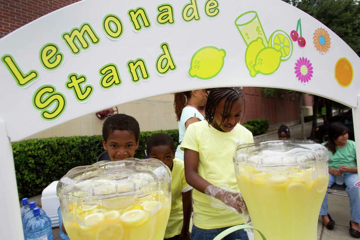 Ke'shawna Curtis, right, pours a glass of lemonade at the Clayton Homes stand during Lemonade Day Sunday, May 6, 2012, in Houston. Youths from across the city set up lemonade stands, to learn how to start, own and operate their own business. The children were working to raise money for a community center at Clayton Homes.