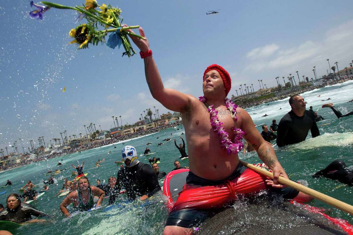 Wally Sani, a friend of Junior Seau, throws some flowers into the ocean off Oceanside, Calif., Sunday, May 6, 2012. A paddle-out was held to honor Seau, who committed suicide in his home Wednesday. Surfers said prayers and gave testimonials about the former football player.