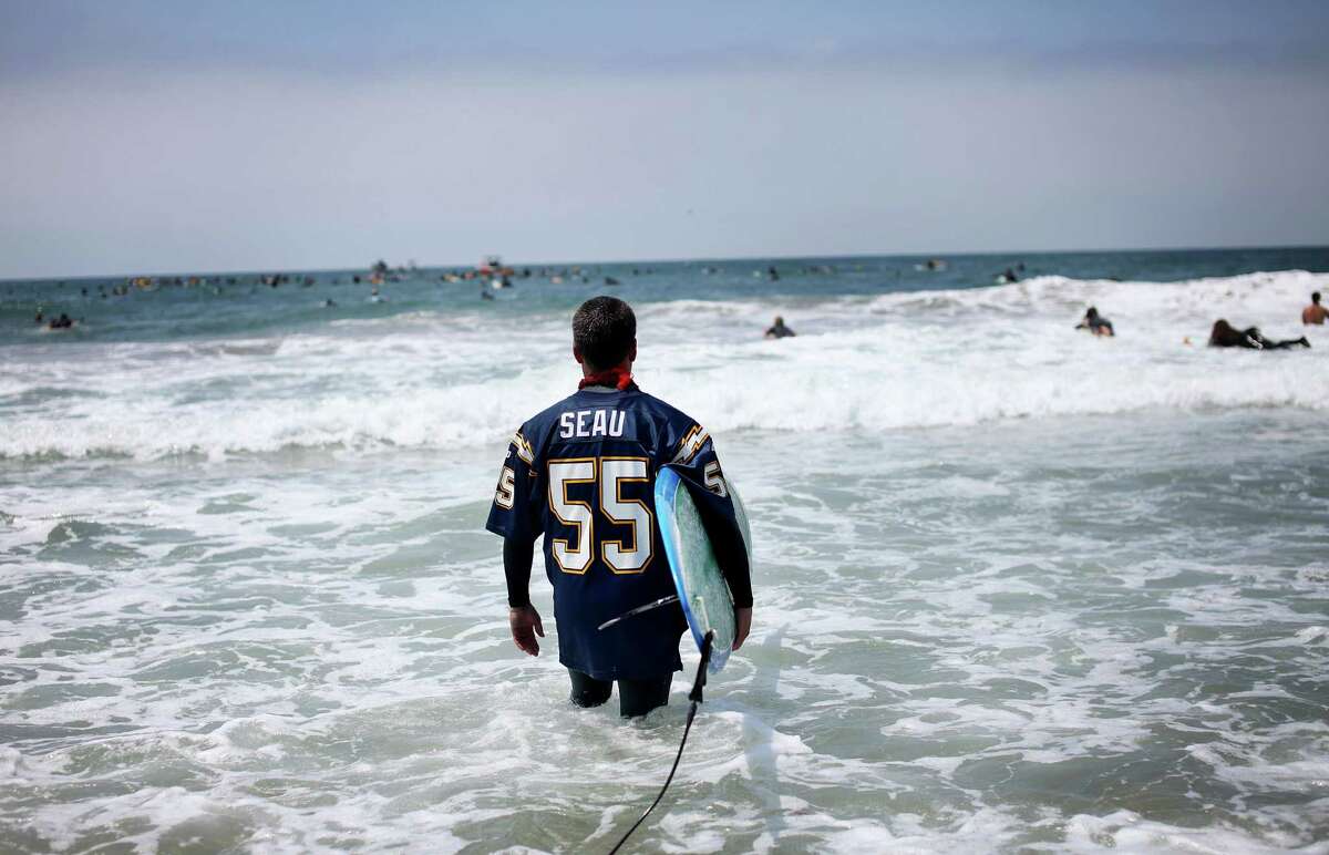 A surfer wades into the surf for a ceremony during a "paddle-out" in honor of NFL star Junior Seau on May 6, 2012 in Oceanside, California. Seau, who played for various NFL teams including the San Diego Chargers, Miami Dolphins and New England Patriots was found dead in his home on May 2nd of an apparent suicide. Family members have decided to donate his brain for research on links between concussions and possible depression.