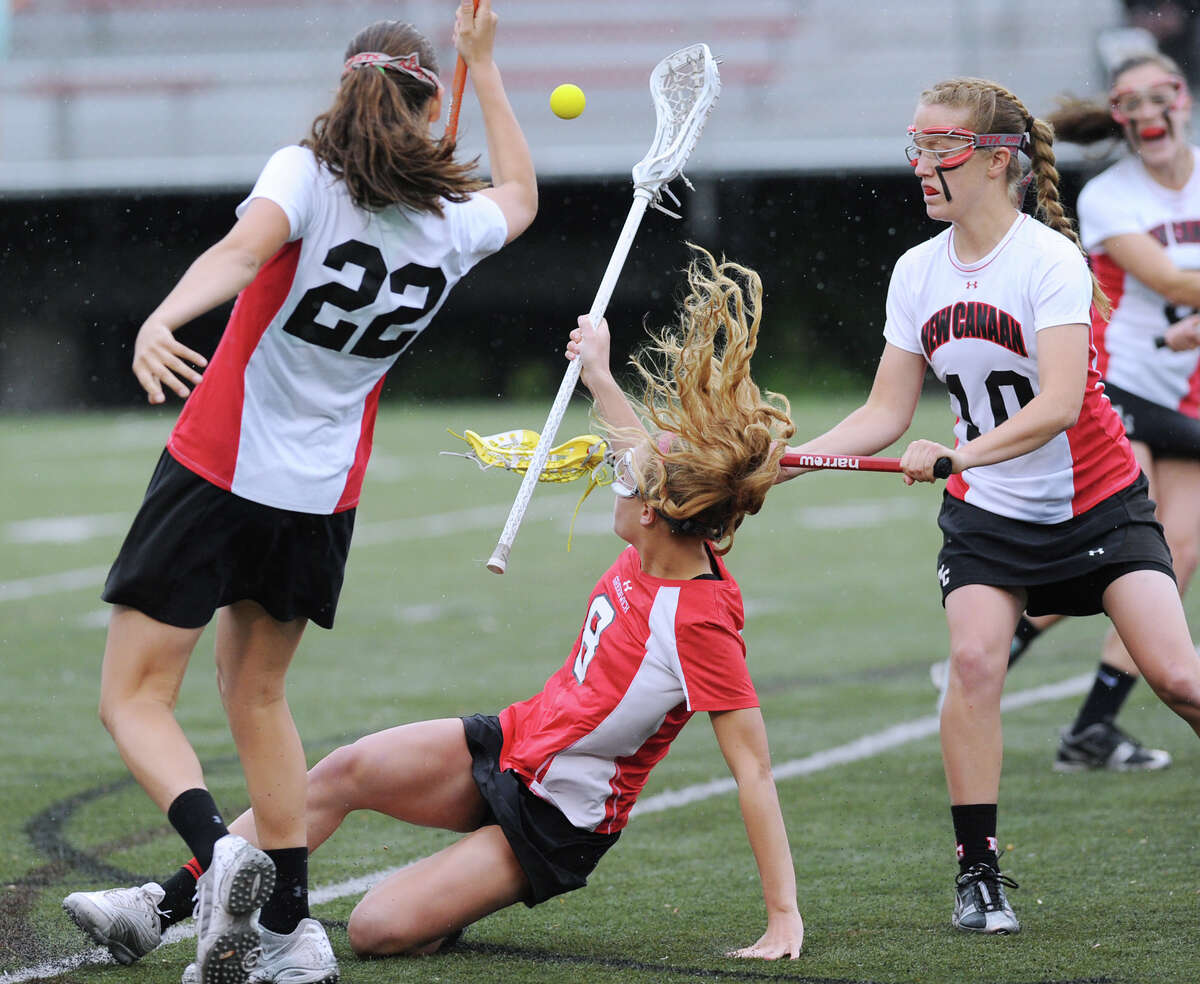 Tori Dunster, center, of Greenwich High School loses teh ball after getting knocked to the ground during the Girls high school lacrosse match between Greenwich High School and New Canaan High School at New Canaan High School, Tuesday, May 8, 2012. At left for New Canaan High School is Olivia Hompe # 22, at right is her teammate Sarah Mannelly #10.