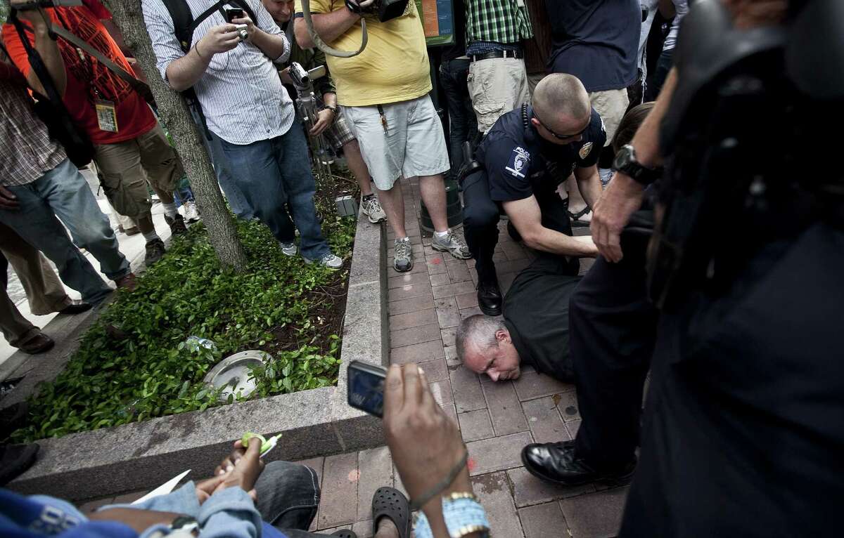 Police officers arrest a protester after he tried to jump a barrier outside of the annual Bank of America Corp. shareholders meeting on May 9, 2012 in Charlotte, North Carolina. Protesters from several movements including the 99 Percent Power movement converged on the annual shareholders meeting to protest a range of issues and actions.