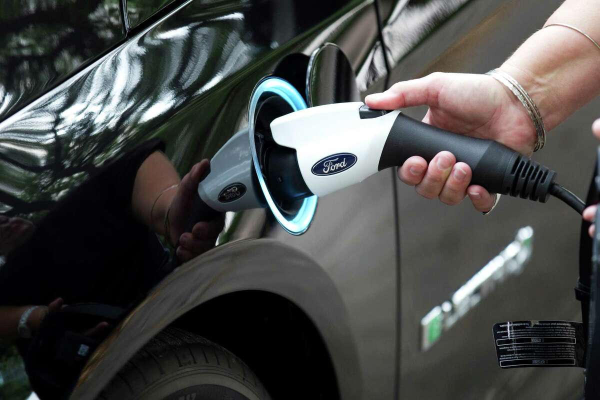 Melanie Gavin demonstrates the use of the electric charing port on the new 2012 Ford Focus Electric near City Hall Thursday, May 10, 2012, in Houston. The battery-powered cars were on display and test drives were offered at Hermann Square Park. The zero-emission, all-electric Ford Focus Electric is expected to arrive in local Ford showrooms in several weeks to several months, Ford spokesman Nik Ciccone said.