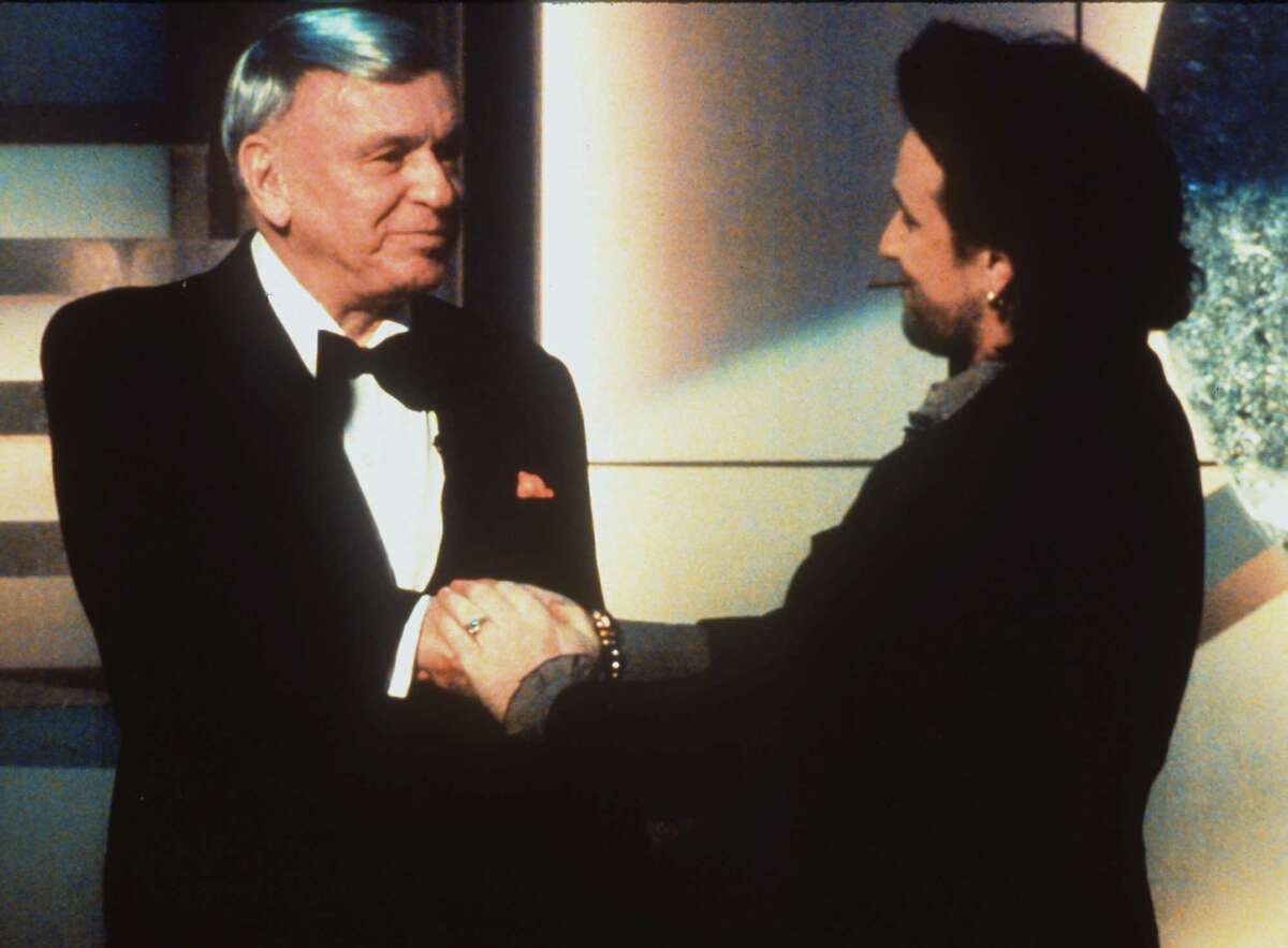Bono shakes hands with Frank Sinatra, left, after he presented the crooner with the Grammy Legend award during the 36th annual Grammy Awards at New York's Radio City Music Hall, in this March 1, 1994 file photo.