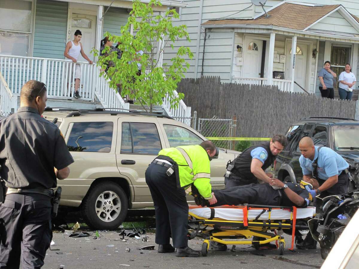 Bridgeport, Conn. police Sgt. Philip Sharpe is put into a neck brace after his cruiser collided head on with a Ford Explorer that police were chasing the wrong way on State Street on Thursday, May 10, 2012.