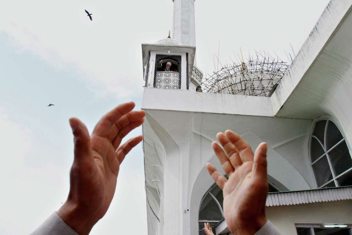 Kashmiri Muslims raise their hands as a head priest, background, displays a relic, believed to be a hair from the beard of the Prophet Mohammad, during special prayers on the death anniversary of Abu Bakr Siddiq, the first Caliph of Islam at Hazratbal Shrine on the outskirts of Srinagar, India, Monday, May 14, 2012. (AP Photo/Mukhtar Khan)