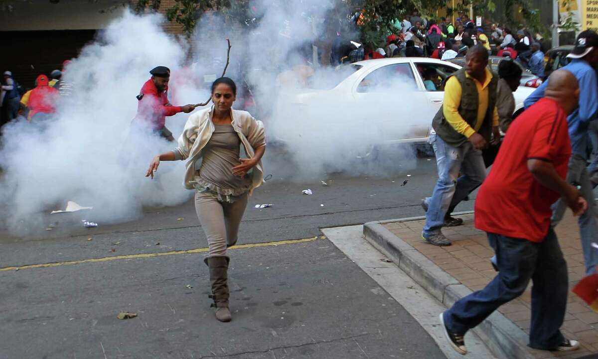 Congress of South African Trade Unions (Cosatu) run for cover after police fired tear gas in Johannesburg, South Africa on Tuesday May 15, 2012. An opposition party march in Johannesburg turned violent Tuesday after union supporters hurled rocks at the leader of South Africa's main opposition party. (AP Photo/Themba Hadebe)