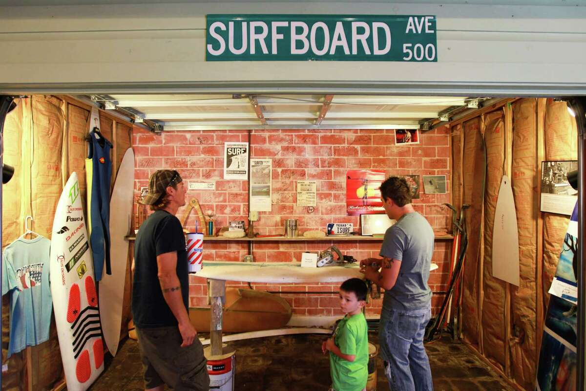 Hector Garza, left, his nephew Kane Garza, center, 4, and brother, Marco Garza, look at a replica of a home surfboard shop. Below, one of the books available in the gift shop.